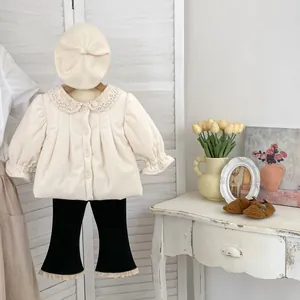 Detail of girls beige corduroy top with lace collar and matching black flared trousers
