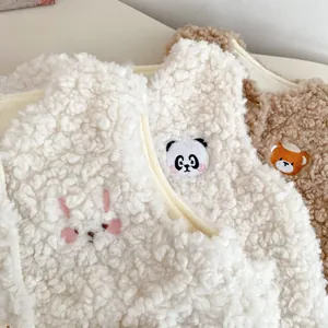 Gros plan de gilets épais en polaire pour enfants avec broderies d'animaux et texture douce