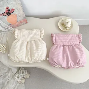 Detailed close-up of bubble gauze rompers with ruffle sleeves in cream and soft pink