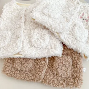 Détail de gilets en laine d'agneau pelucheuse crème et marron avec broderie lapin