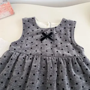 Detail eines grauen Baby-Mädchenkleides mit Polka Dots, schwarzer Schleife und Plüschfutter