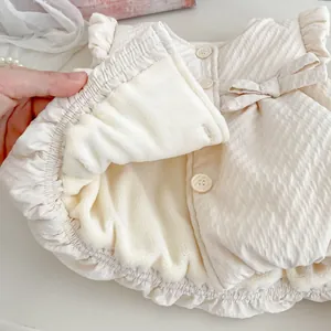 Thick off-white baby vest with textured outer fabric, fleece lining and bow detail