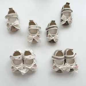 Detail of floral baby shoes with lace bows and 3D cherry accents on soft sole flats