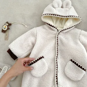 Detail der Baby-Winterjacke mit Sherpa-Textur und braunem Zickzack-Besatz an der Tasche