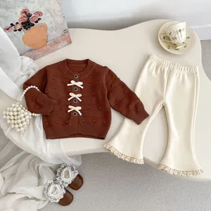 Detailansicht der Baby-Strickjacke mit Schleifen und Schlaghose mit Spitzenbesatz