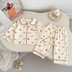 Detalle de pijama de bebé con estampado de oso y ribetes rosas en algodón color crema