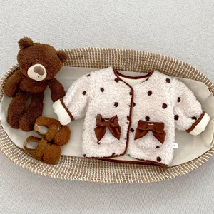 Dettaglio di calda giacca neonato in pile beige con pois marroni e fiocchi carini