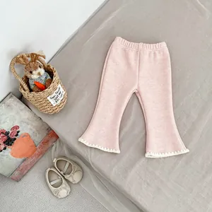 Detail of pink flared toddler trousers with lace trim hem and soft textured fabric