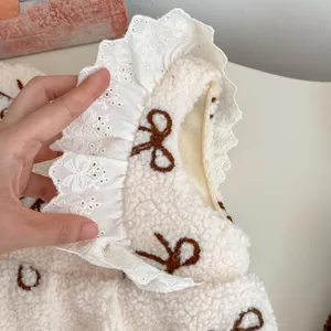 Detailed view of the white fleece fabric with lace collar and bow embroidery