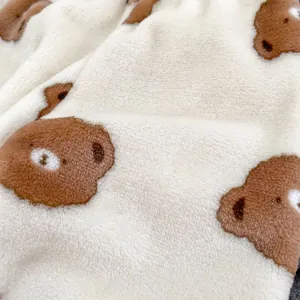Gros plan sur le tissu polaire beige doux avec motif d'ours brun pour enfants