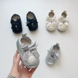 Détail de chaussures Mary Jane pour bébé avec nœuds en noir, beige et argenté