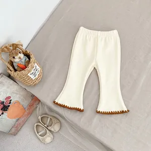 Close-up of cream flare pants featuring elastic waist and brown scalloped crochet edges