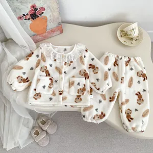 Detail van de baby pluche pyjama met kanten kraag en bruine beer patronen