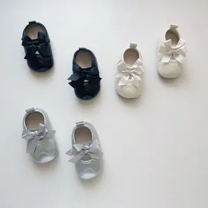 Détails des chaussures de marche bébé avec nœud en couleurs noir, beige et argenté brillant