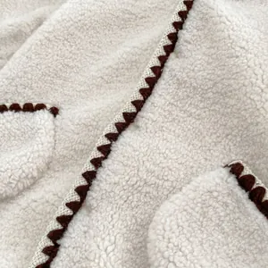 Detail der Baby-Einteiler mit Sherpa-Fleece-Textur und brauner Dreiecks-Randbestickung