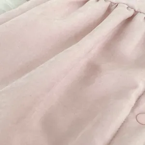 Detail eines rosa Baby-Einteilers mit geraffter Stoffstruktur und passendem Harzknopf