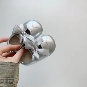 Détail de chaussures bébé Mary Jane argentées avec doublure peluche et grand nœud satin
