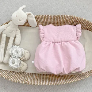 Detail of light pink baby romper with ruffle sleeves and textured fabric in a basket