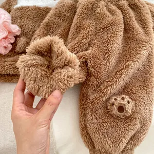 Close-up of thick brown coral fleece fabric with detailed bear paw embroidery detail