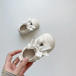 Détail de chaussure bébé princesse avec grand nœud en satin blanc et cuir PU souple