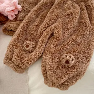 Close-up of baby pajama set showing thick brown coral fleece fabric and paw embroidery