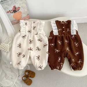 Detail of soft fleece baby jumpsuits with bow patterns and delicate lace trim accents