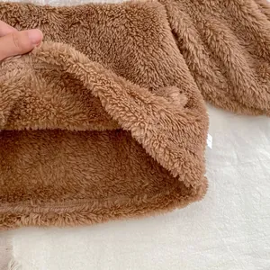 Detailed close-up of brown coral fleece fabric showing thick and warm teddy plush texture