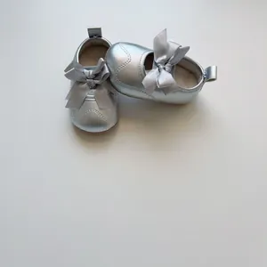 Détail de chaussures Mary Jane argentées pour bébé avec grand nœud en soie et coutures