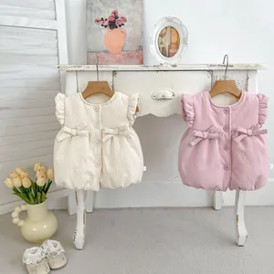 Detail of infant textured vests with ruffles and bows in pink and cream beige