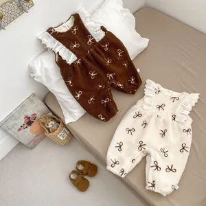 Detail of baby fleece rompers showing lace frill edges and bow embroidery on soft fabric