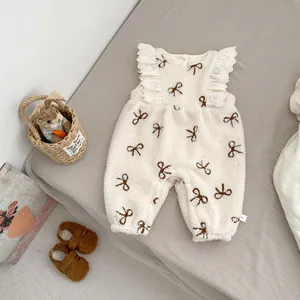 Detail of fleece baby romper with brown bow prints and delicate white lace flutter sleeves