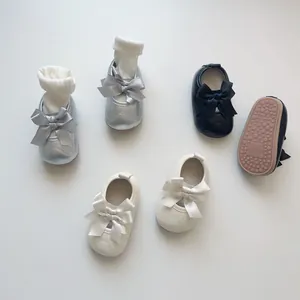 Détail des chaussures de princesse pour bébé avec nœuds en argent, noir et blanc