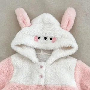 Detail of baby plush pajamas featuring soft coral fleece and cute rabbit ear hood design