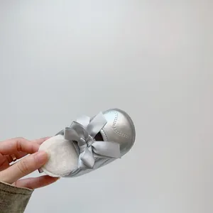 Détail de chaussures argentées pour bébés filles avec doublure pelucheuse et nœud gris