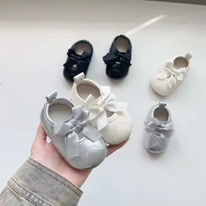 Détail de trois chaussures de marche bébé en argent, crème et noir avec des nœuds en satin