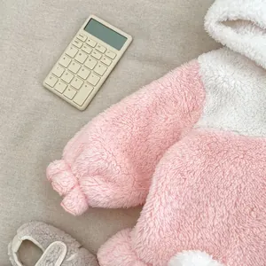 Detail of pink and white coral fleece baby romper with elastic cuffs and matching soft shoes