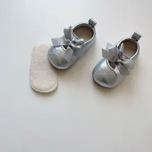 Gros plan de chaussures bébé argentées avec nœud en satin et semelles en peluche