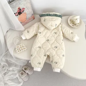 Detail of floral embroidery and quilted texture on cream hooded baby winter romper