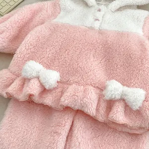 Detail view of pink coral fleece pajamas showing plush texture, bows and ruffle hemline