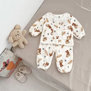 Detail van een baby pyjamaset van fleece met berenprints en kanten kraag op zachte stof