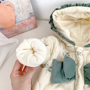 Detail of floral quilted baby romper with warm fleece lining and frill hooded collar