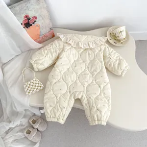 Detail eines gesteppten Baby-Einteilers mit Blumenmuster, Spitzenkragen und Bündchen