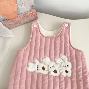 Detailed shot of pink quilted baby vest featuring three white plush bunny embroideries