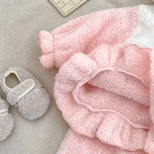 Detailed view of pink coral fleece baby pajama set with ruffled trim and soft infant shoes