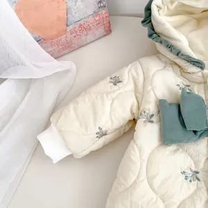 Close-up of quilted floral embroidery and ruffle trim on a warm baby winter romper