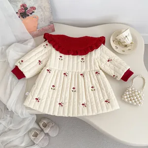 Detail of mushroom embroidery on girl's quilted winter jacket with red ruffle collar