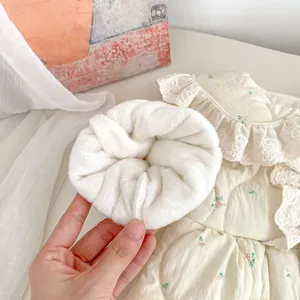 Nahaufnahme von weißem Plüsch-Haargummi und gestepptem Baby-Strampler mit Blumenmuster