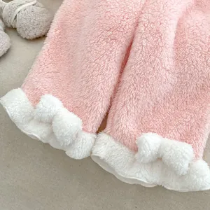 Detailed view of pink coral fleece baby pants with fluffy white cuffs and bows