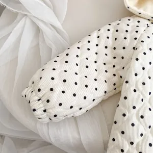 Detailed view of quilted baby hooded jacket with black polka dots and elastic cuffs