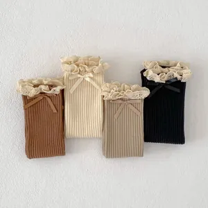 Detail of four pairs of cotton socks with delicate lace edges and satin bows in earth tones